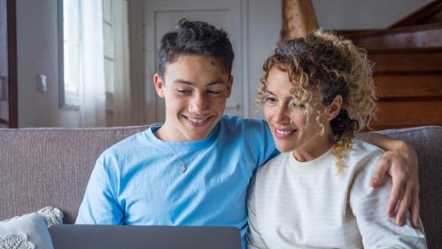 A parent and child look at the screen of a laptop computer