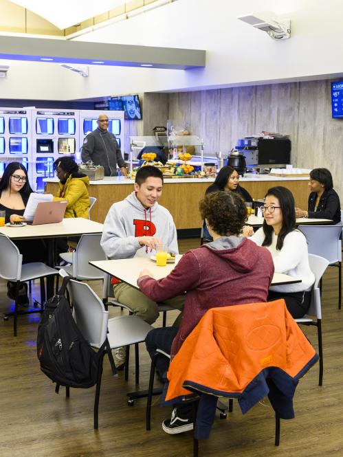 Students sitting in a dining area talking and eating.
