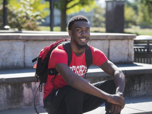 A student sits outdoors on some sunny steps